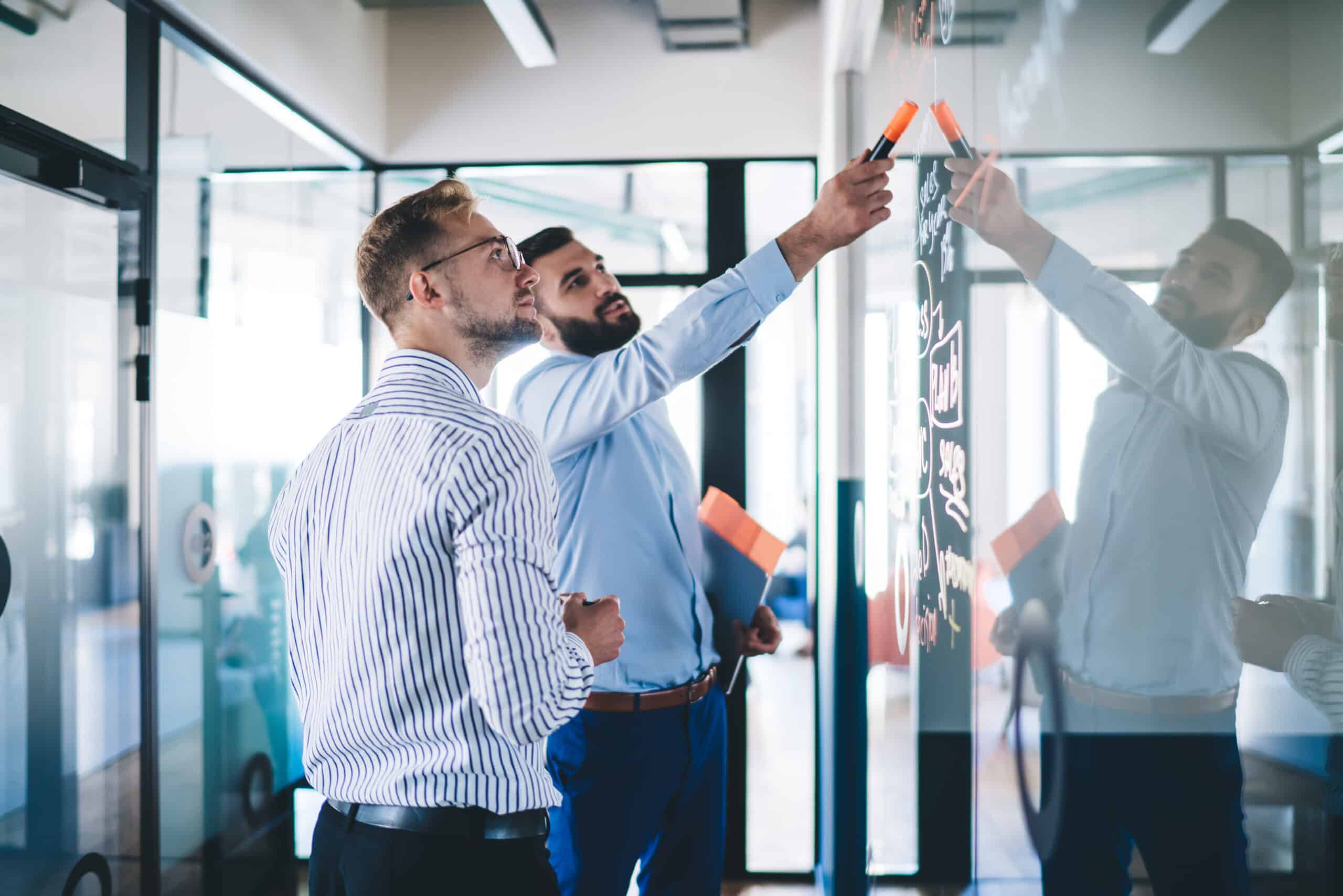 Confident male employee pointing on notes standing with colleagues
