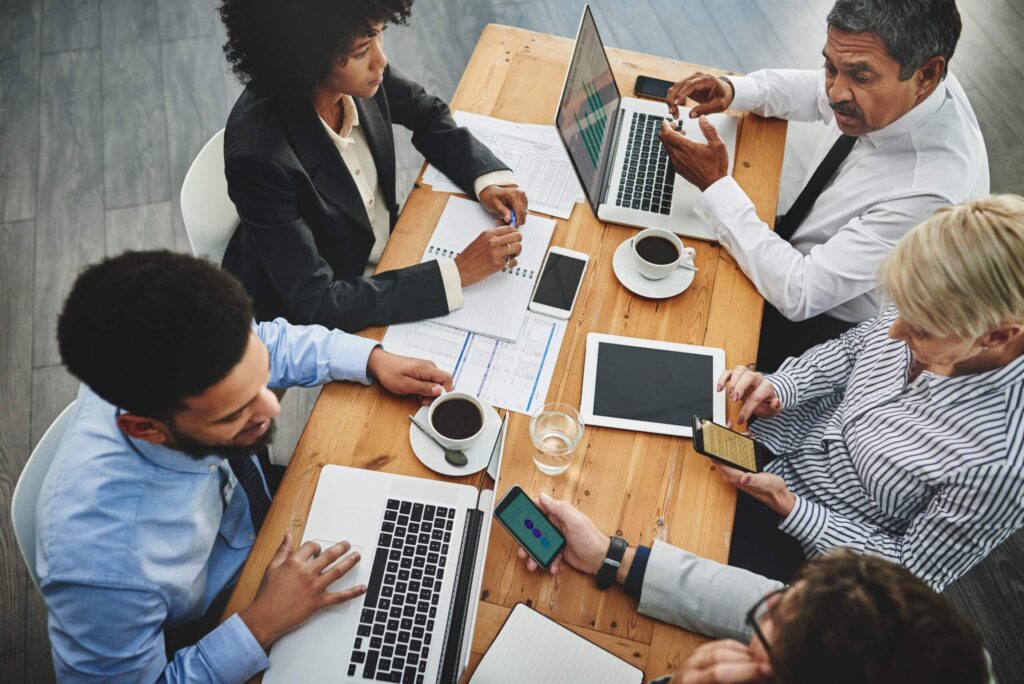 Working from their multiple devices. Shot of a group of businesspeople having a meeting in an office.
