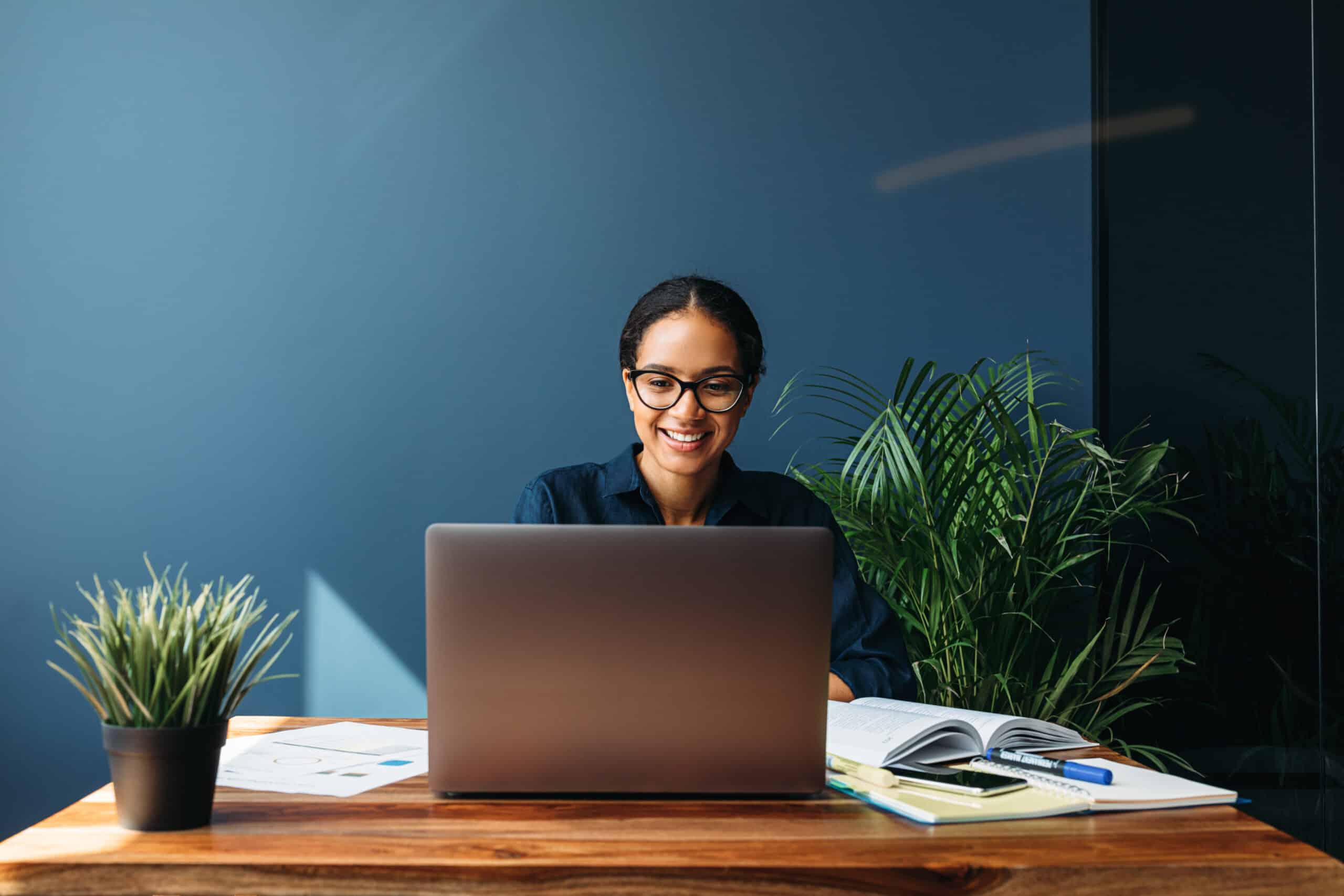 Smiling entrepreneur sitting at home working on laptop computer